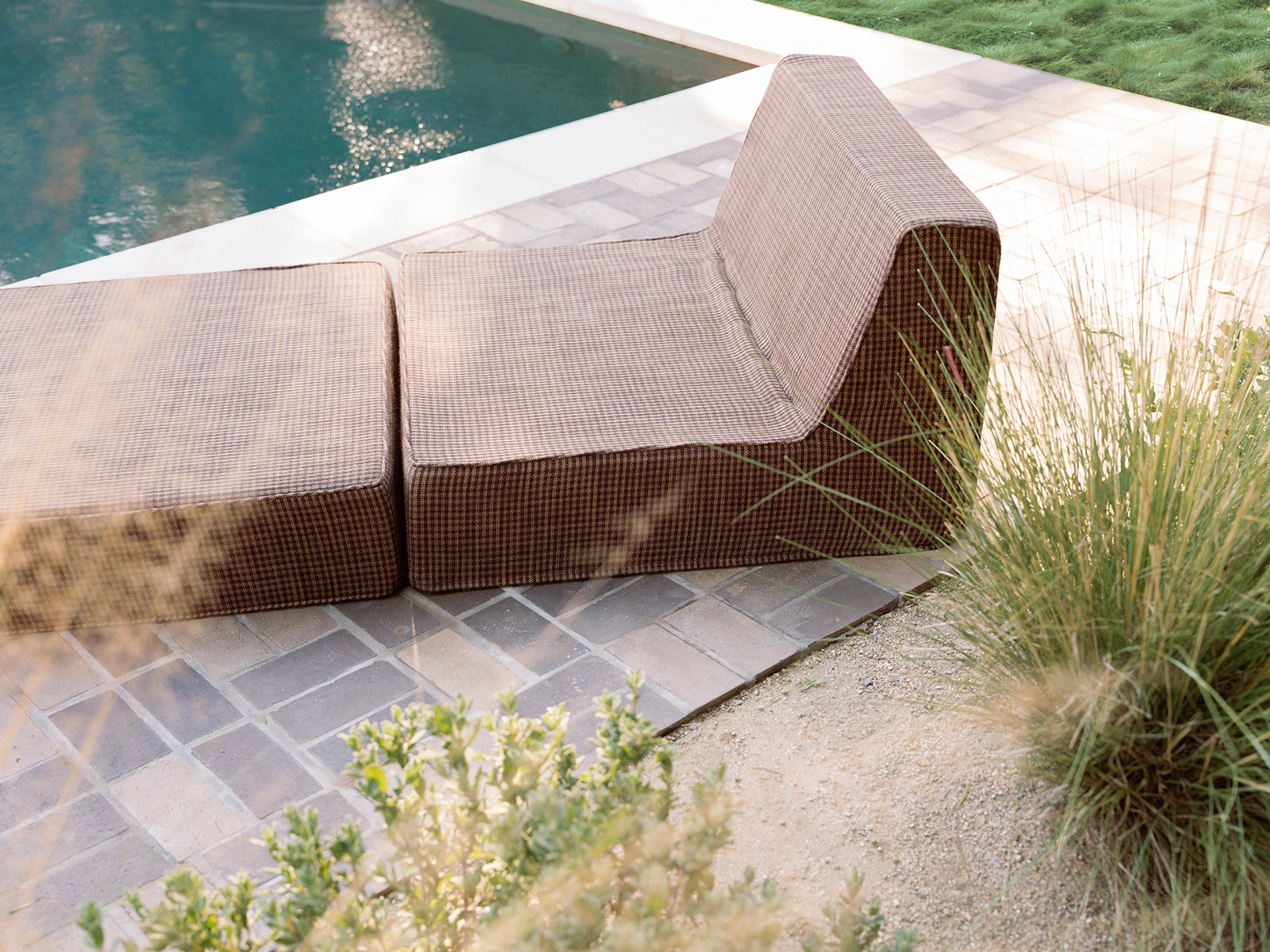 Brown folding outdoor lounge chaise by pool