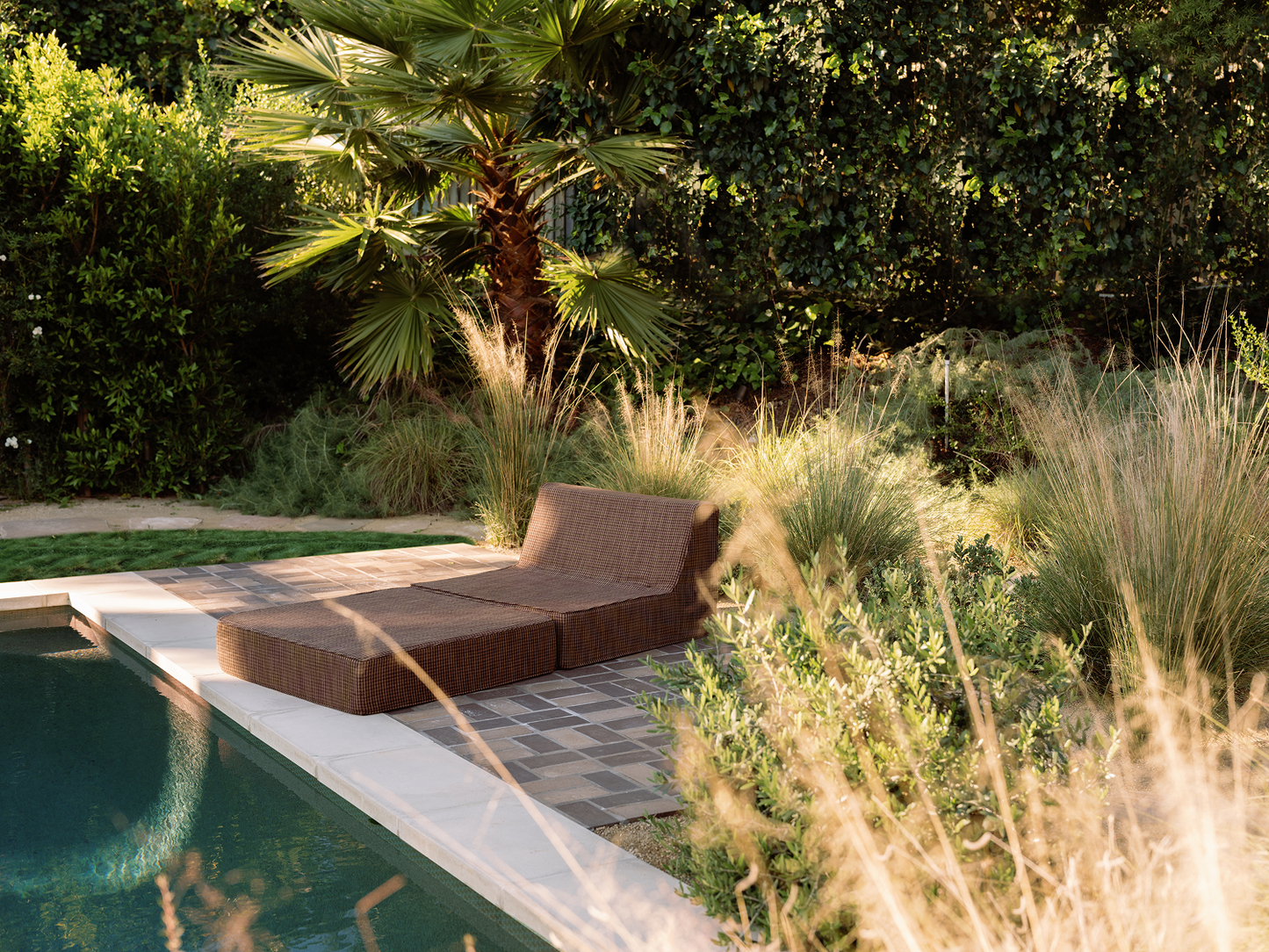 Brown folding outdoor lounge chaise by pool