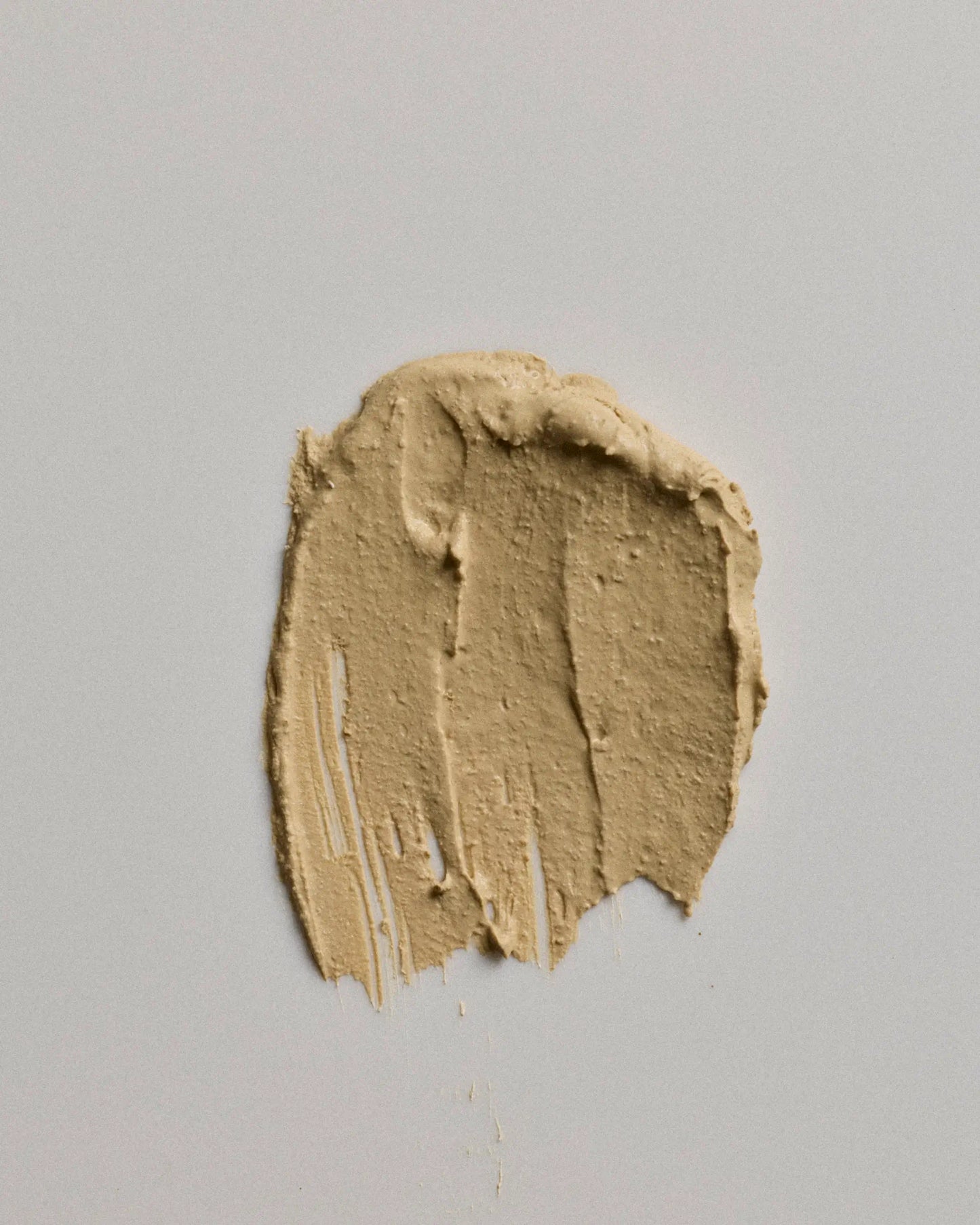 A textured smear of canvas earth coat on a neutral light gray background.