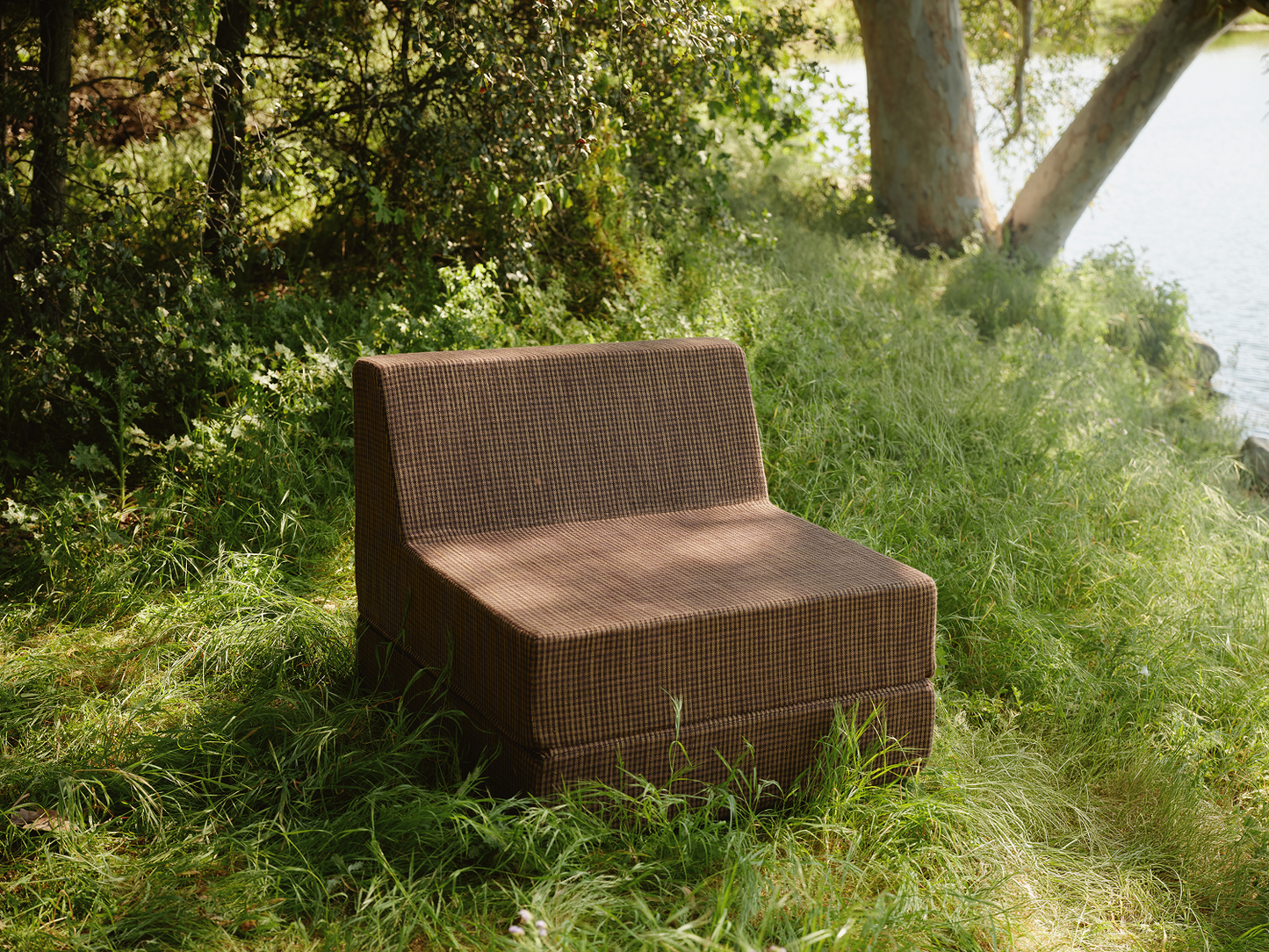 Brown folding outdoor lounge chaise in meadow