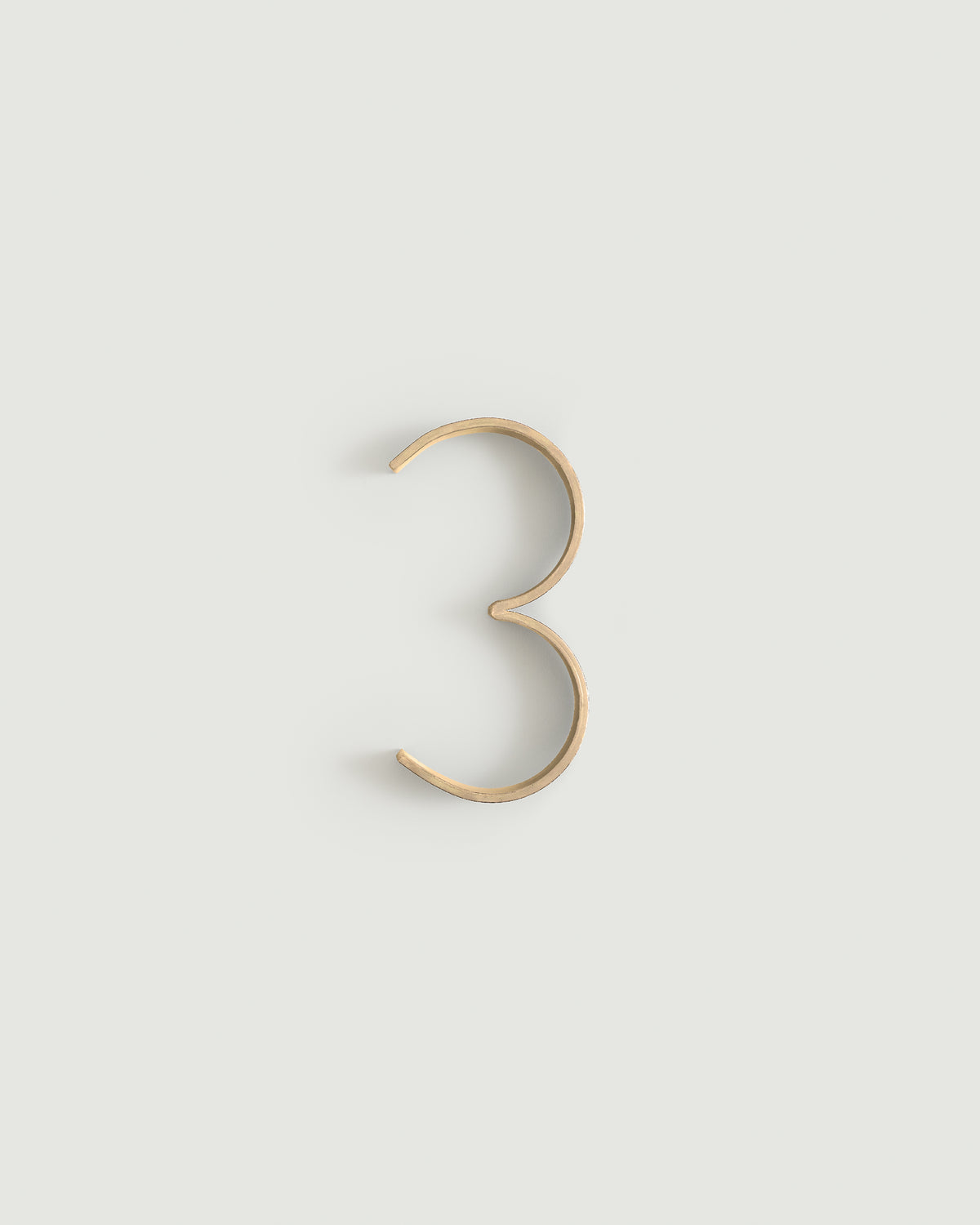 Raw brass house number three