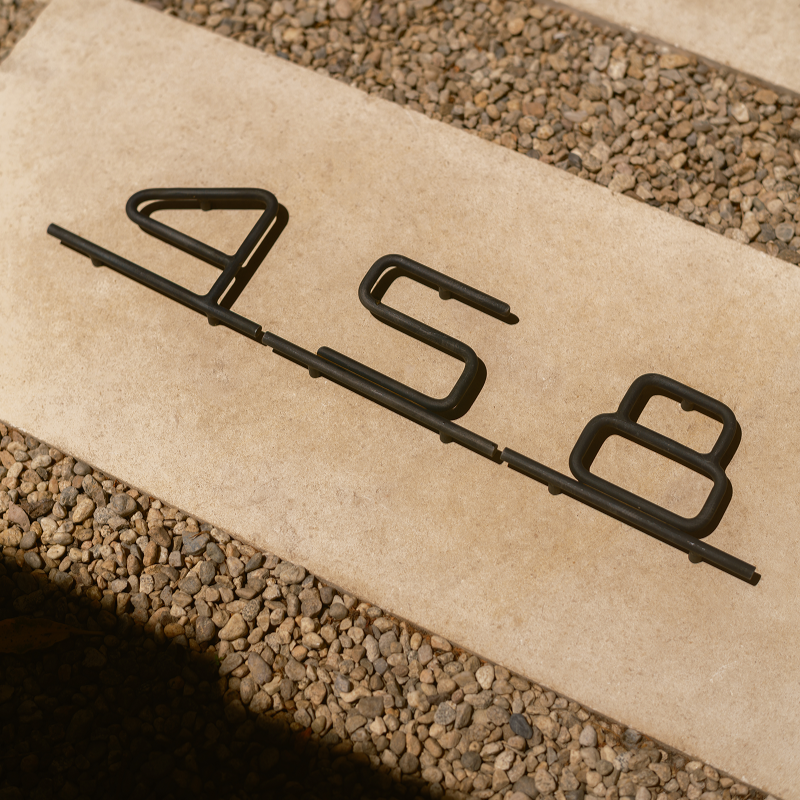 Blackened steel '458' house numbers on a beige background