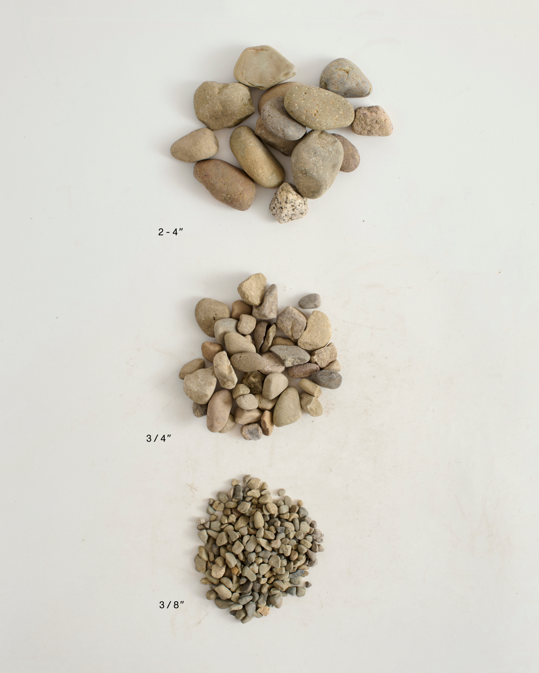 Three piles of rocks of different sizes on a white background