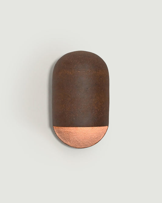 A modern wall-mounted light fixture with a dark brown textured upper dome  made of clay, shown against a light gray background.