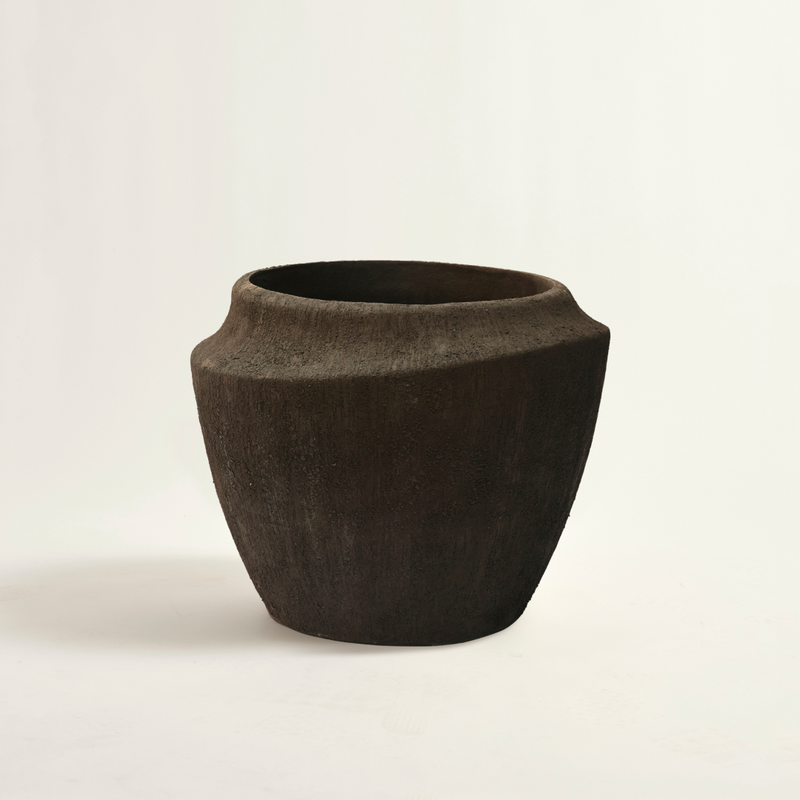 Dark brown ceramic pot on a light beige background