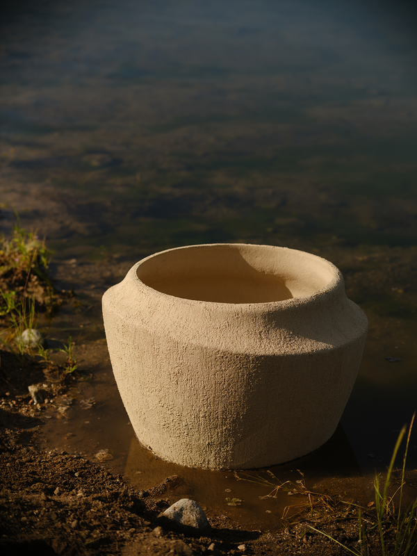Ceramic pot on a muddy bank with water in the background