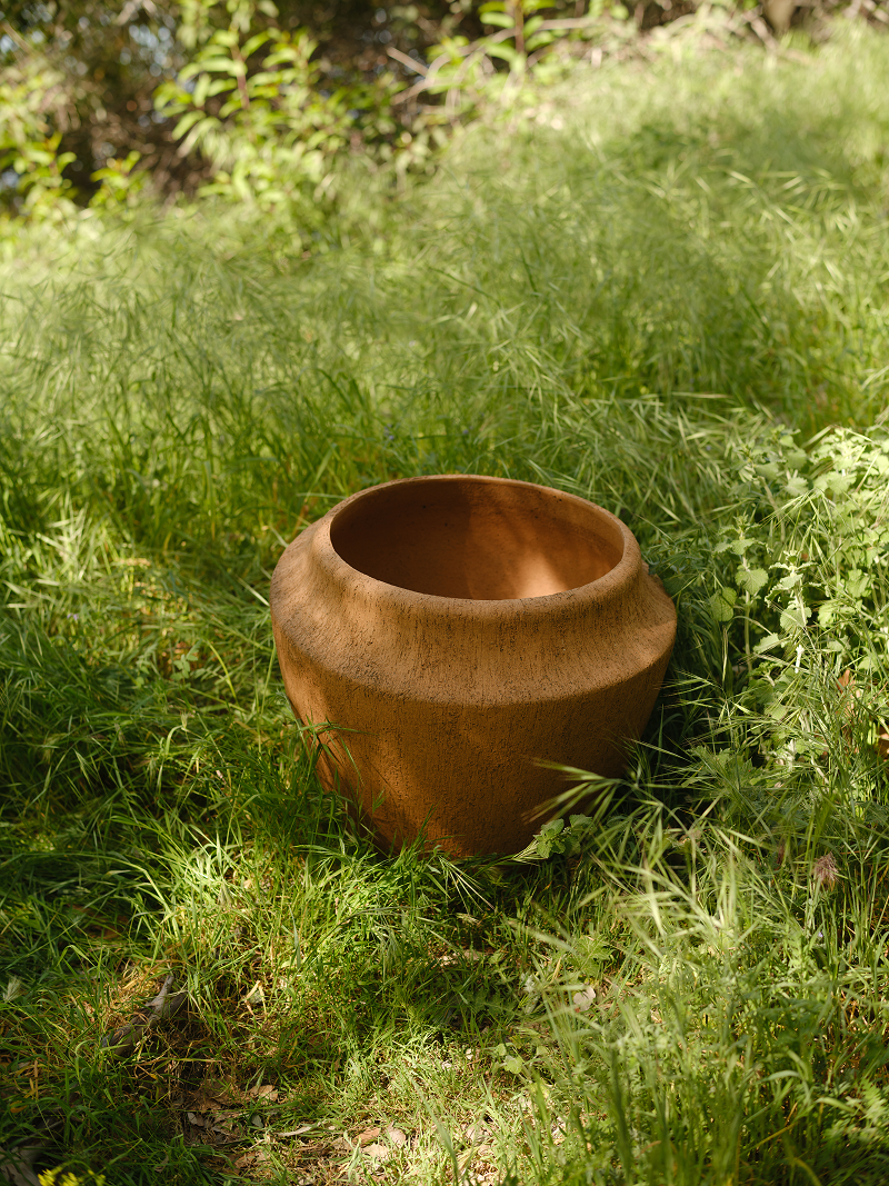 Brown pot in a grassy outdoor setting