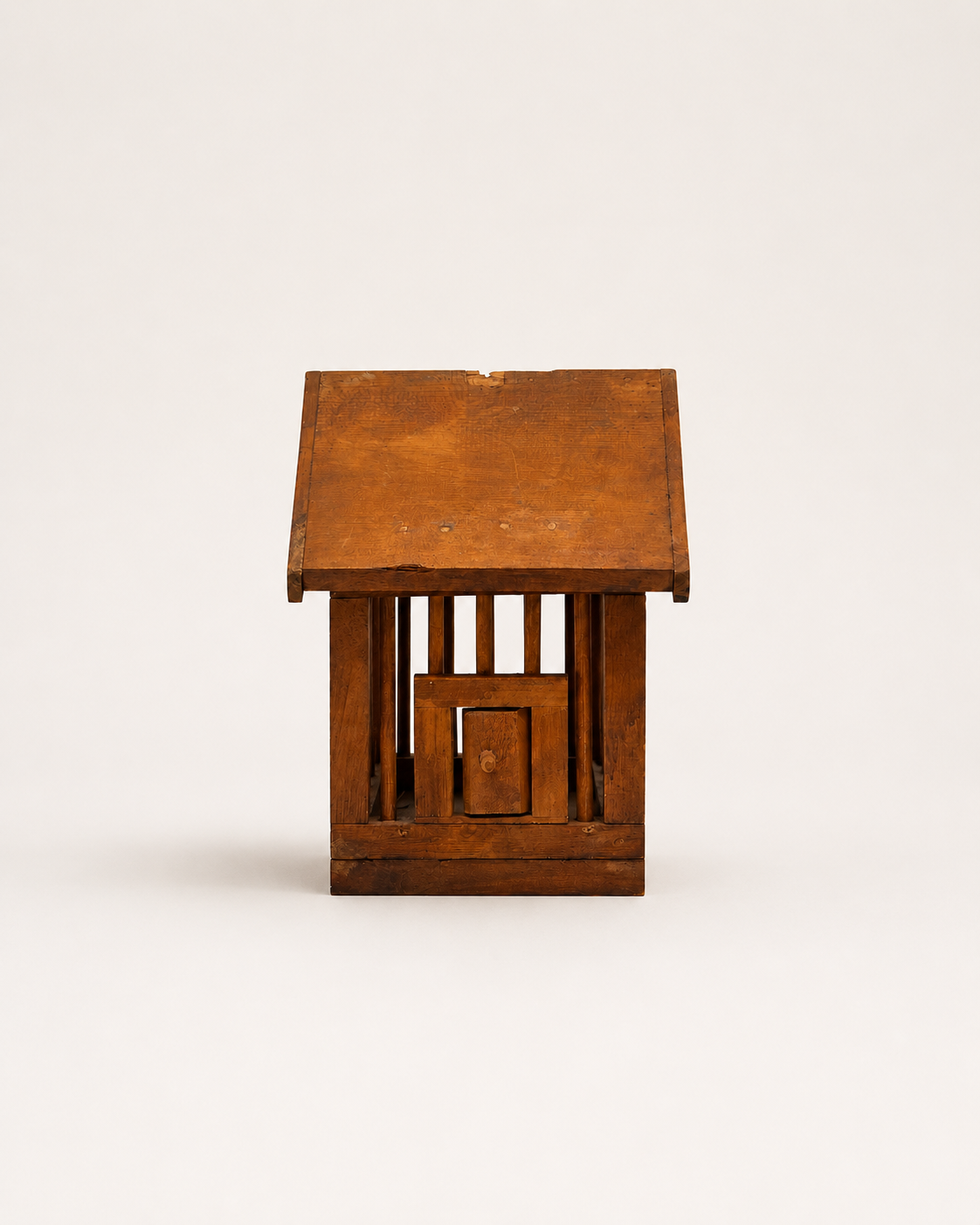 A small rustic wooden birdhouse with a slatted front and a pitched roof, photographed against a plain light background.