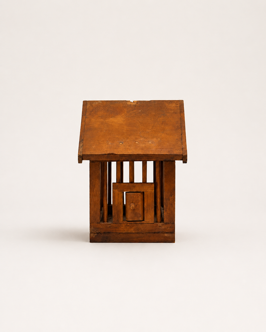 A small rustic wooden birdhouse with a slatted front and a pitched roof, photographed against a plain light background.