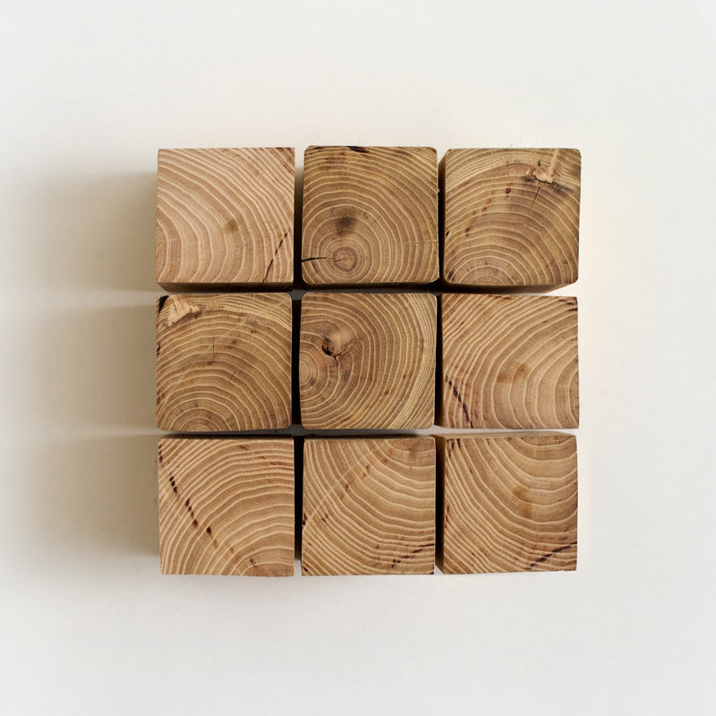A collection of square wood pavers arranged in a grid pattern, showcasing the natural wood grain and ends.