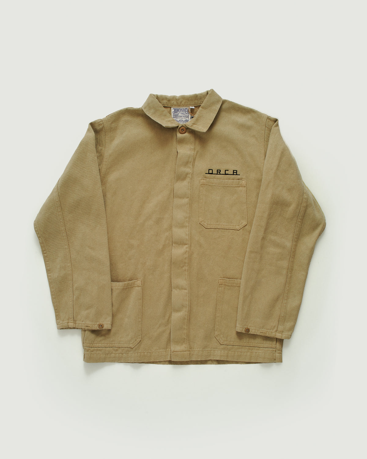 beige field jacket, orca logo on front above pocket