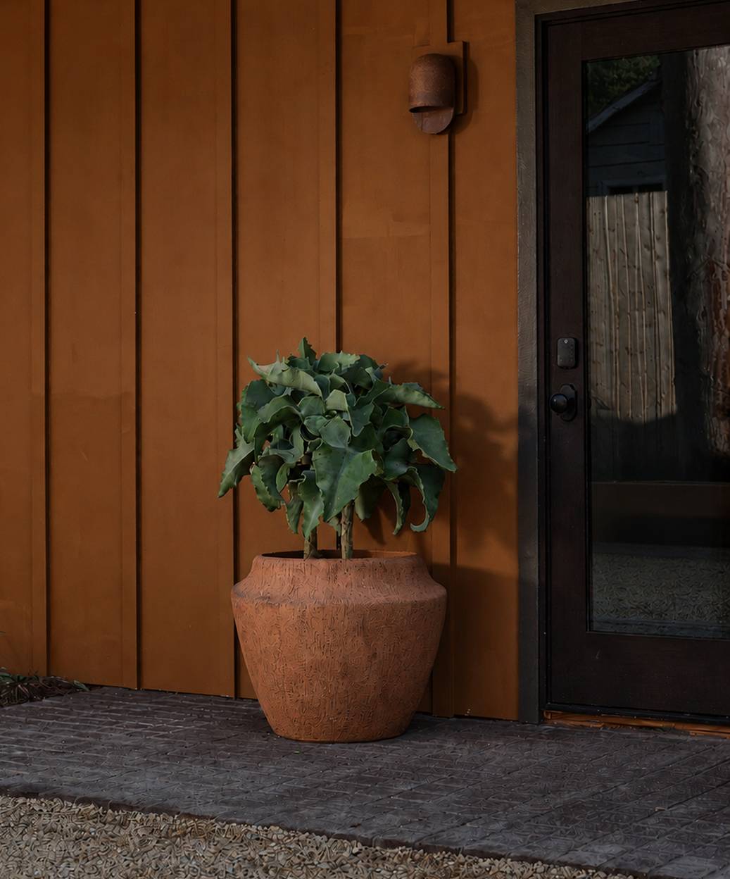 Clay outdoor planter sitting on brick in front of door 