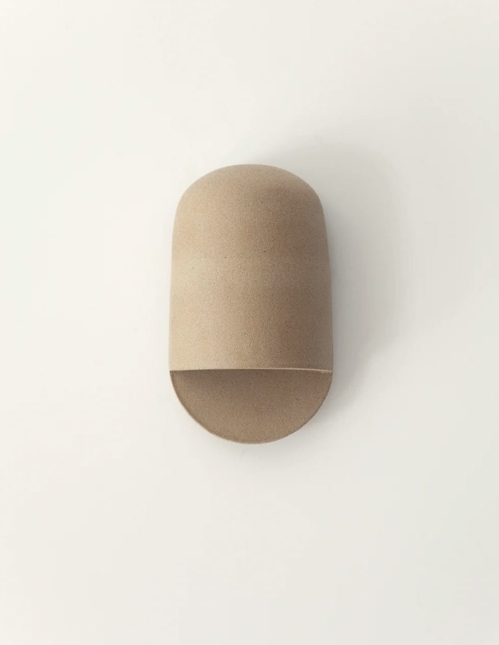 A minimalist, dome-shaped wall sconce in a natural light brown wood finish, mounted on a plain white wall.