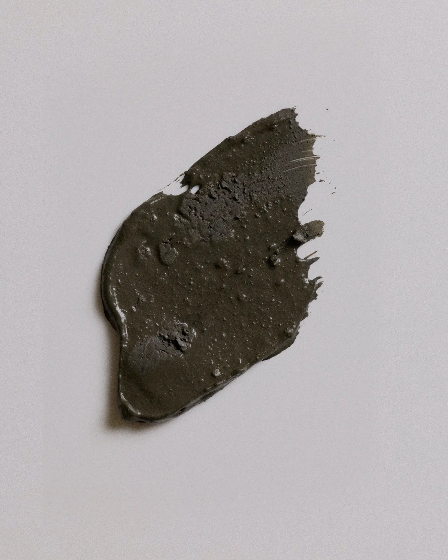 A smudge of camouflage earth coat on a plain light gray background.