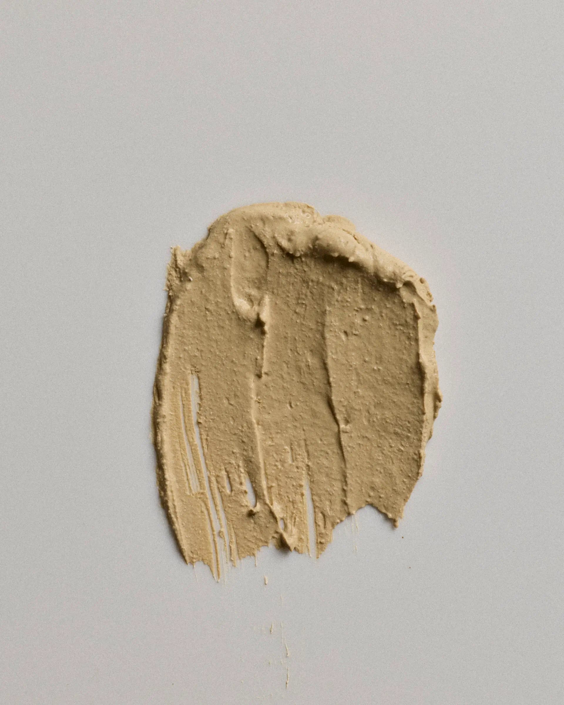 A textured smear of canvas earth coat on a neutral light gray background.