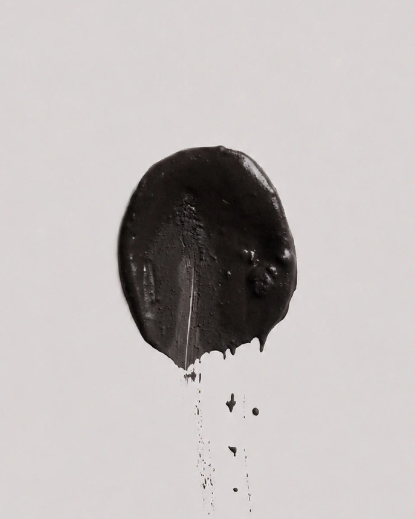 Dusk earth coat on a plain light gray background, with a few small drips below.