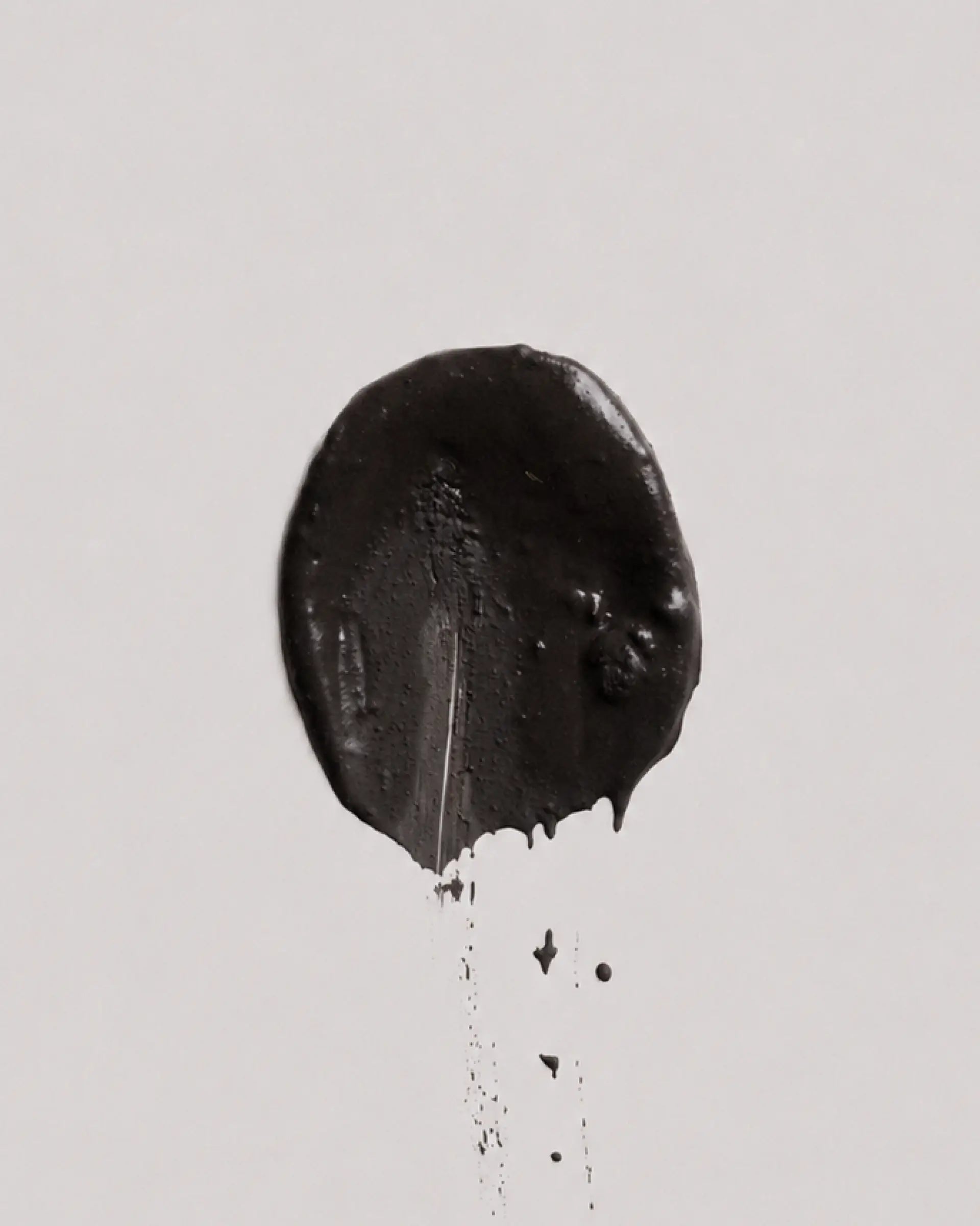 Dusk earth coat on a plain light gray background, with a few small drips below.