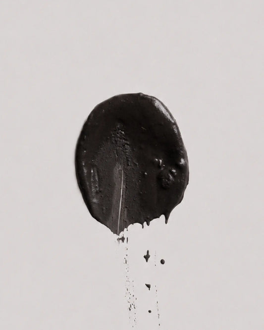 Dusk earth coat on a plain light gray background, with a few small drips below.