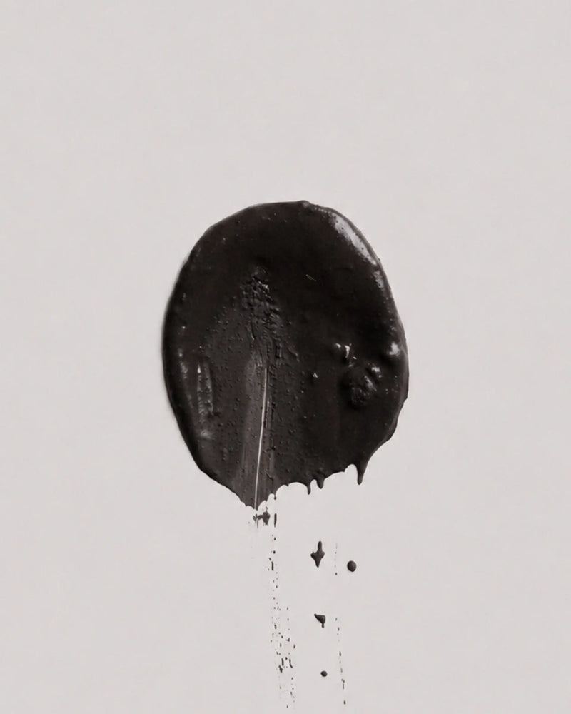 Dusk earth coat on a plain light gray background, with a few small drips below.