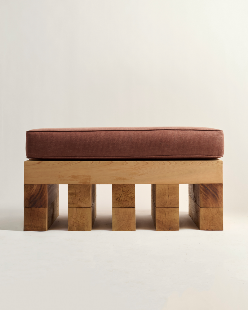Wooden ottoman with a Burgundy cushion on a light background