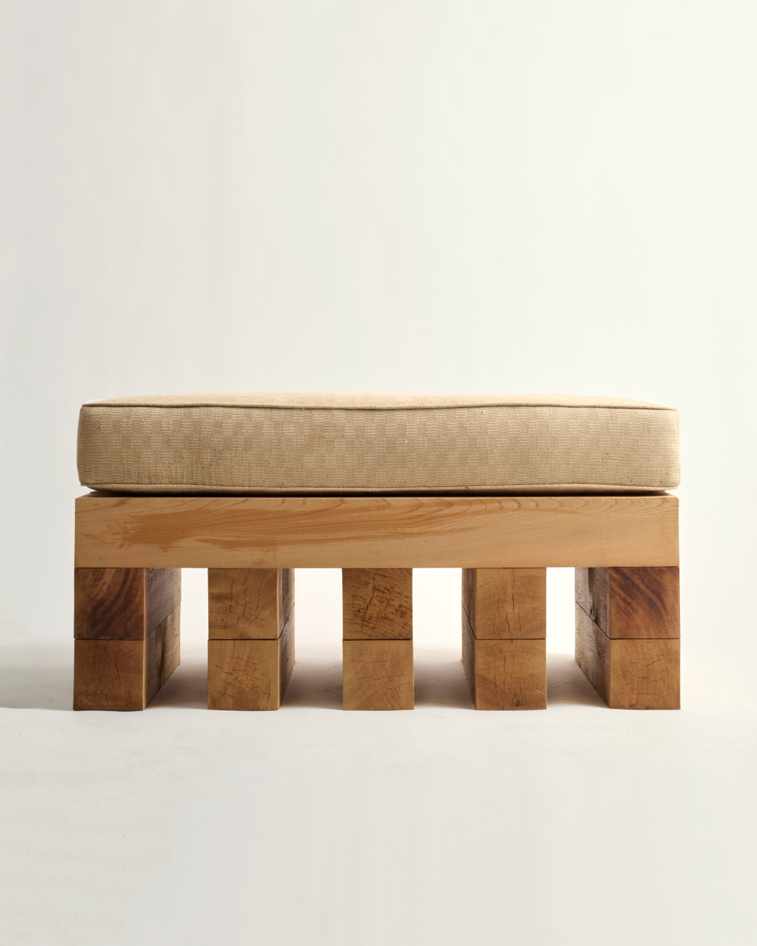 Wooden ottoman with a beige cushion on a white background