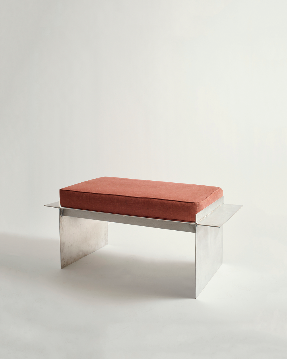 Metal bench with red cushion and white background