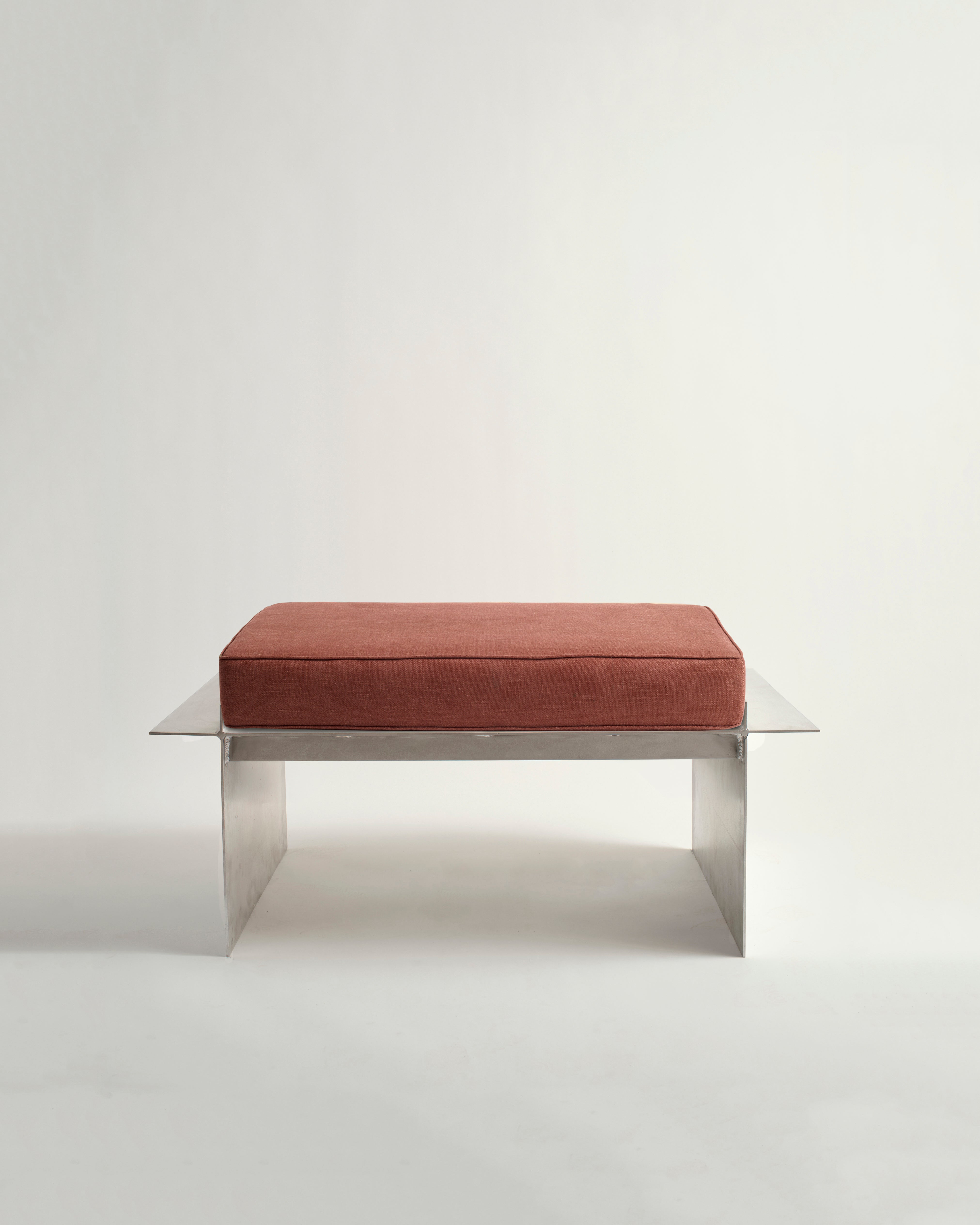 Metal bench with white background and red cushion