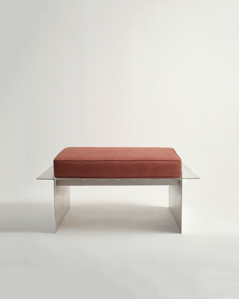 Metal bench with white background and red cushion