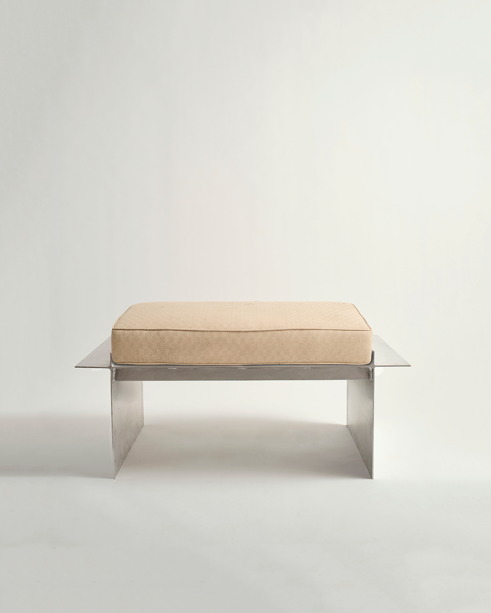 Metal bench with white background and cream cushion