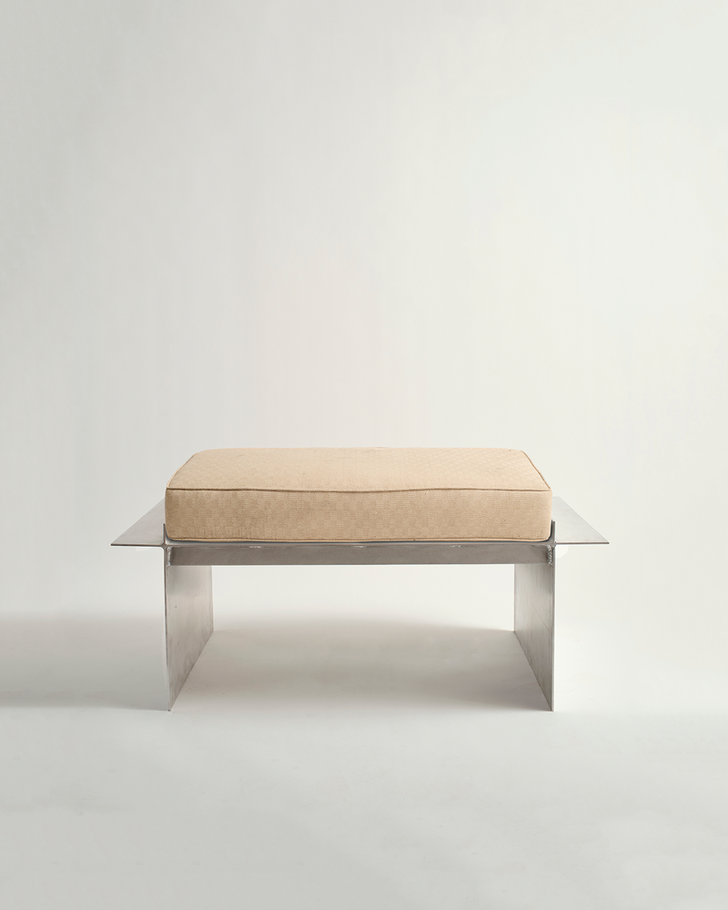 Metal bench with white background and cream cushion