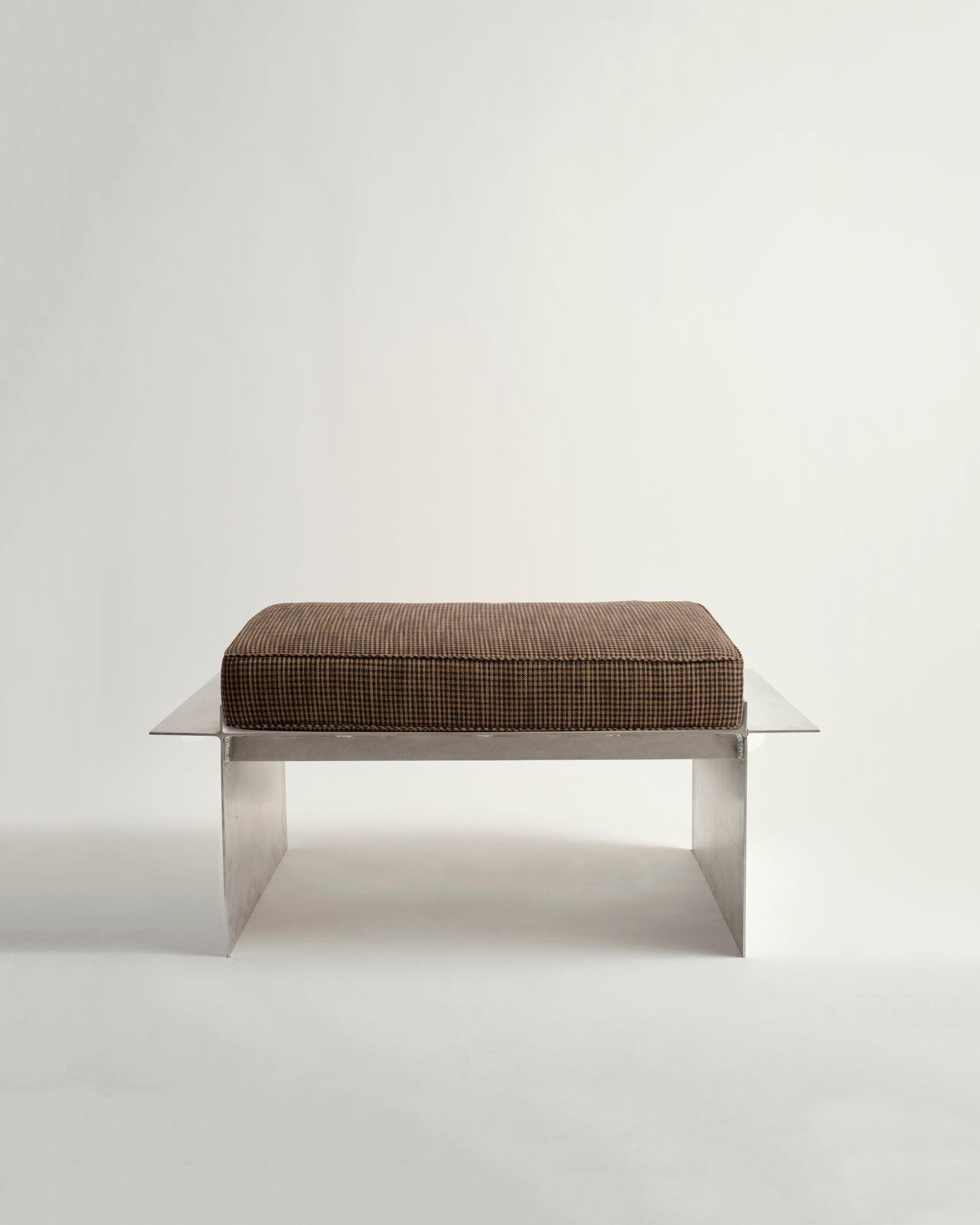 Metal bench with white background and brown cushion