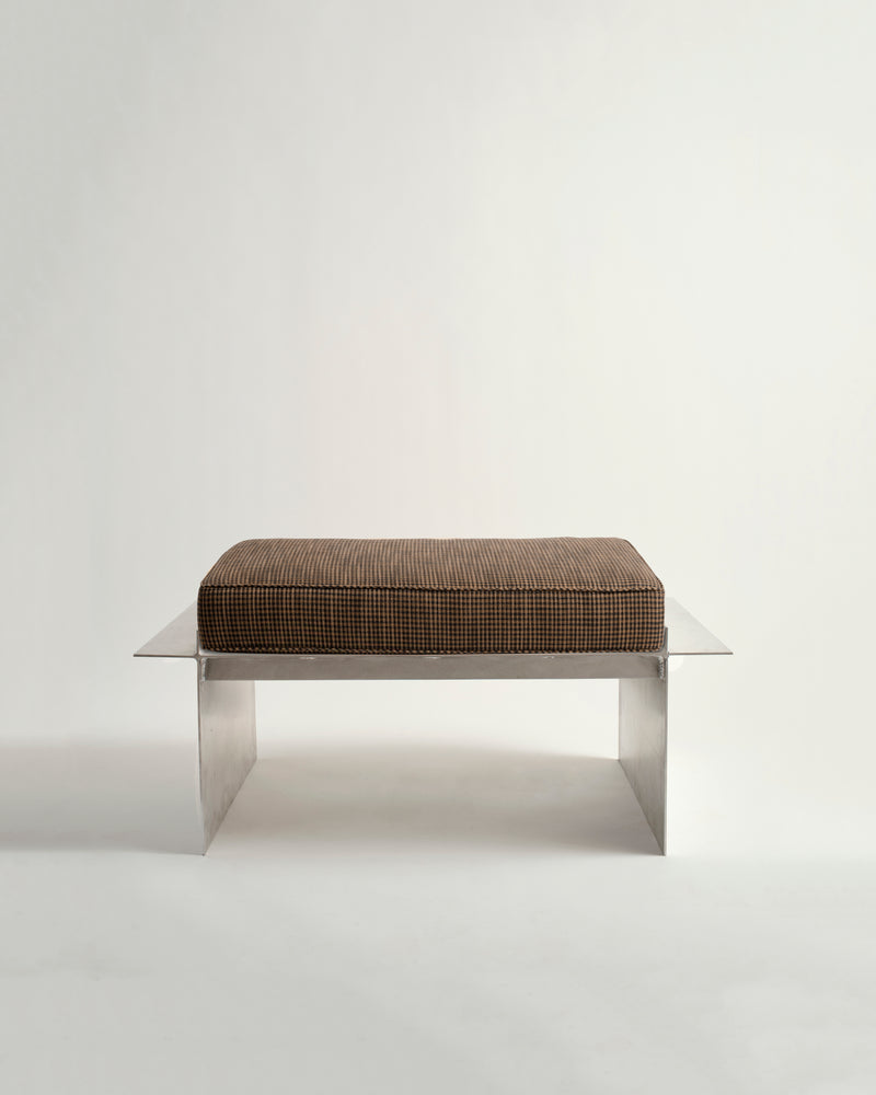 Metal bench with white background and brown cushion