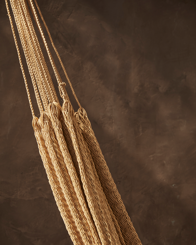 Close-up of a textured brown fabric with a tassel on a matching background