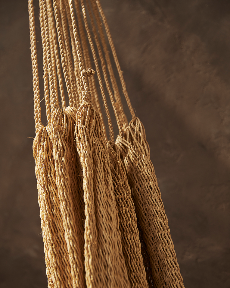 Close-up of a woven rope hammock against a brown background