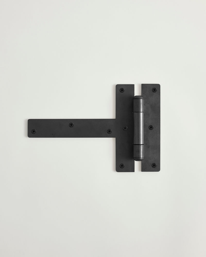 Blackened brass hinge on a light gray background