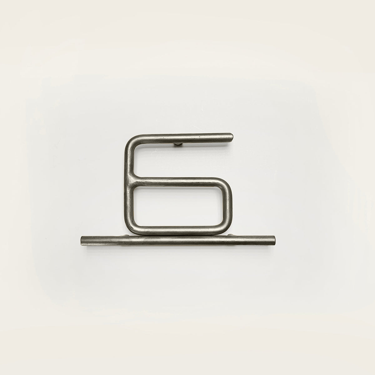 Silver house number '6' on a white wall 
