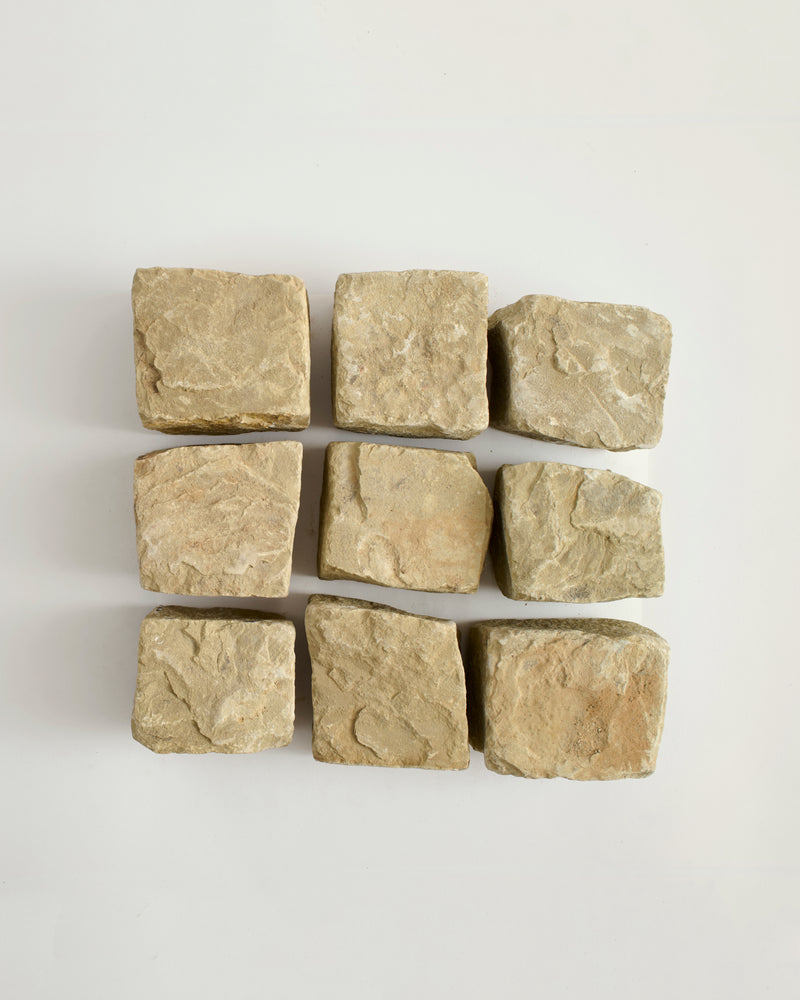 Nine square stone cobble stones arranged in a 3x3 grid on a light gray background