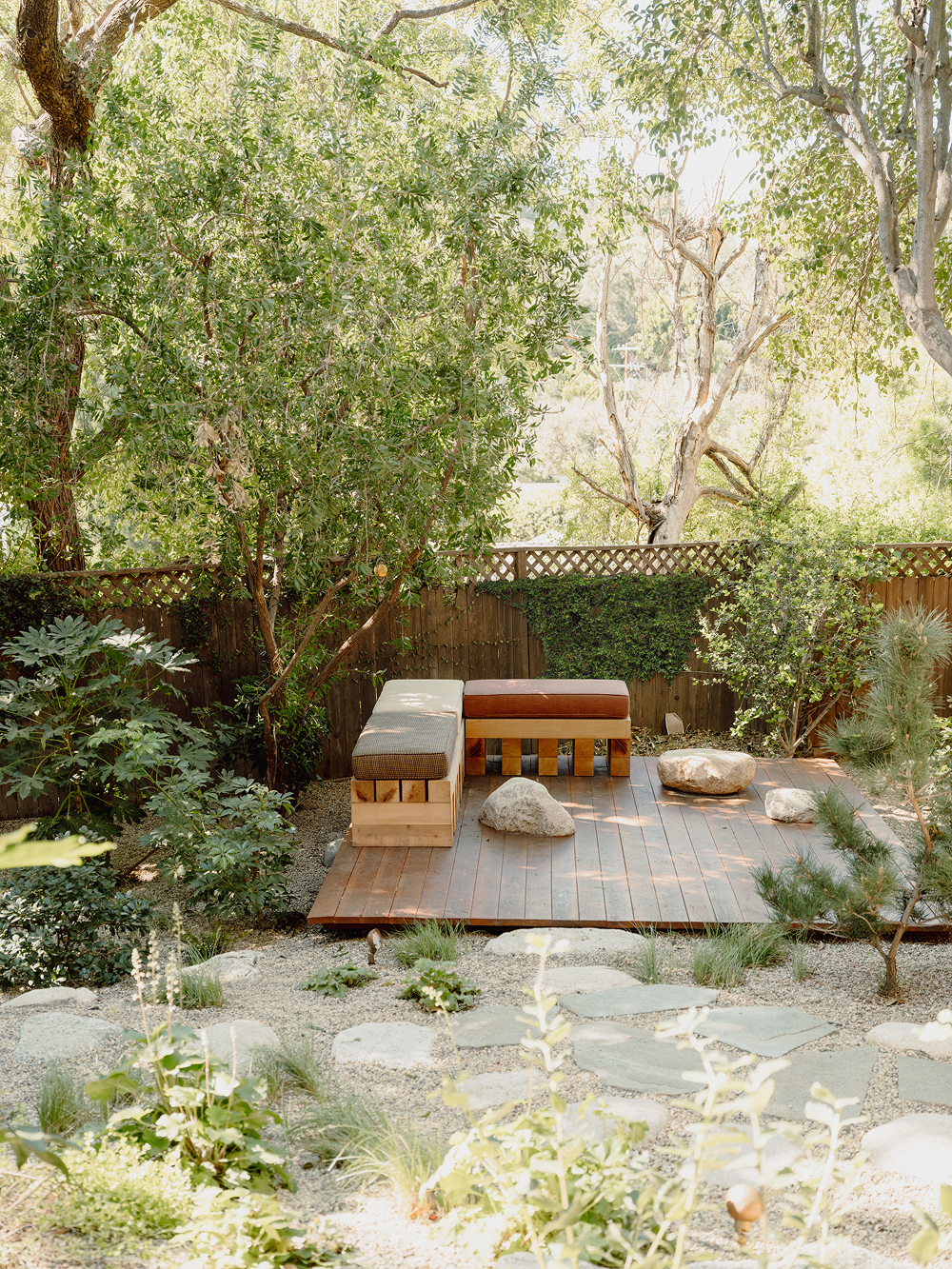 Outdoor patio area with wooden furniture surrounded by greenery