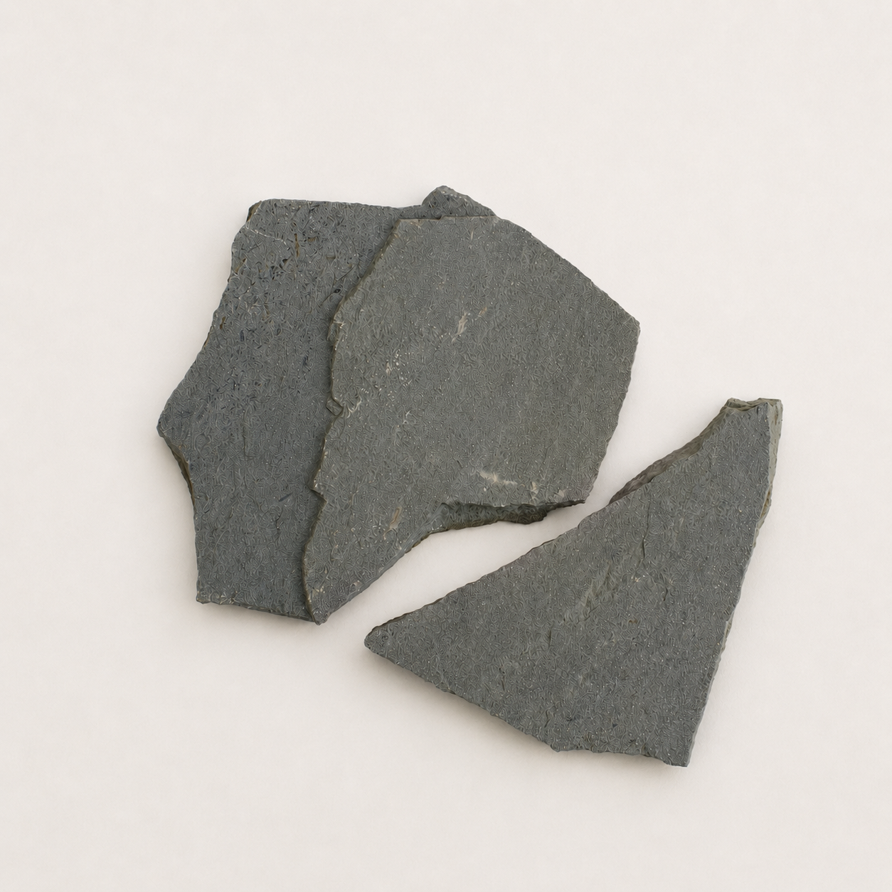 Three irregular Flagstone mist rock chips with natural rough textures, arranged on a plain off-white background.