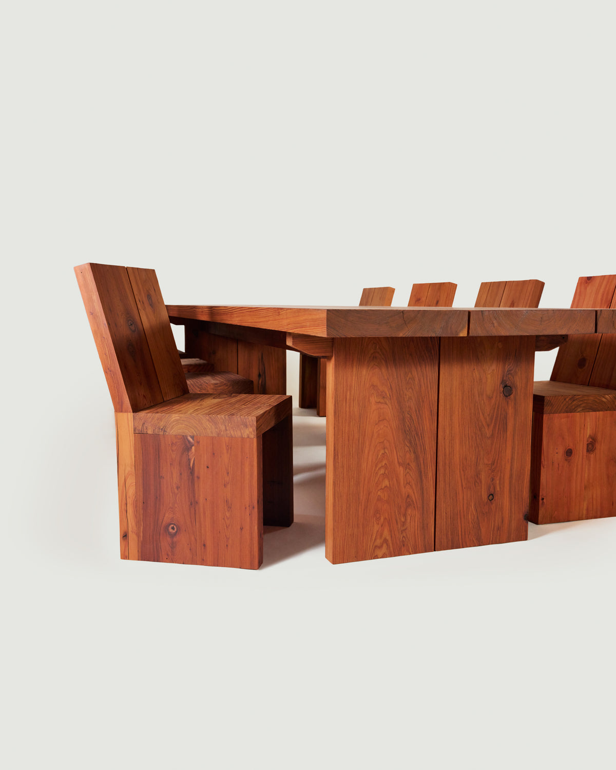 A wooden dining table set with matching block-style chairs, shown against a clean off-white background.