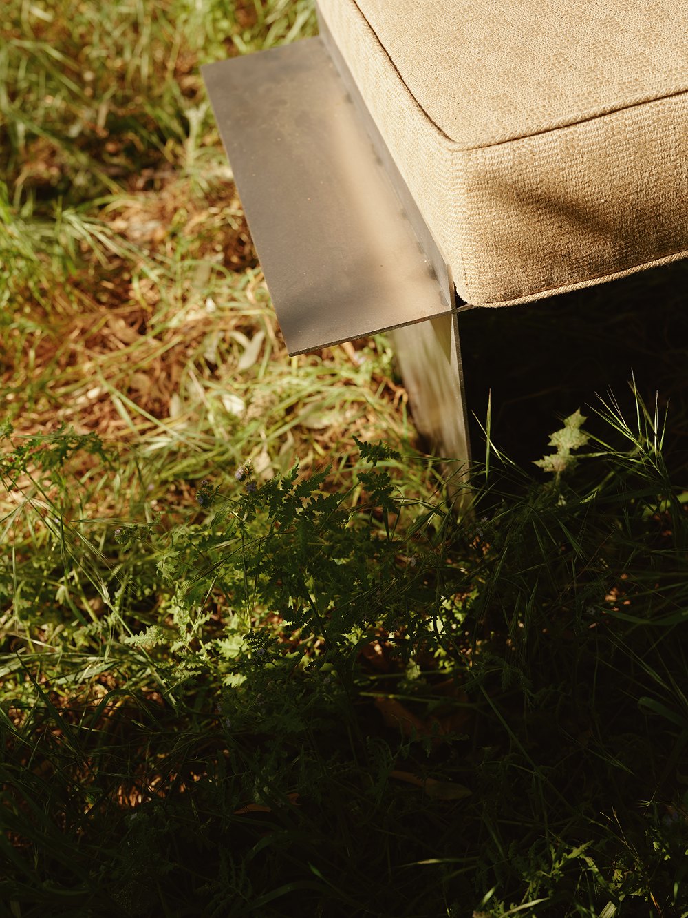 Detail of metal bench and cream cushion in field 