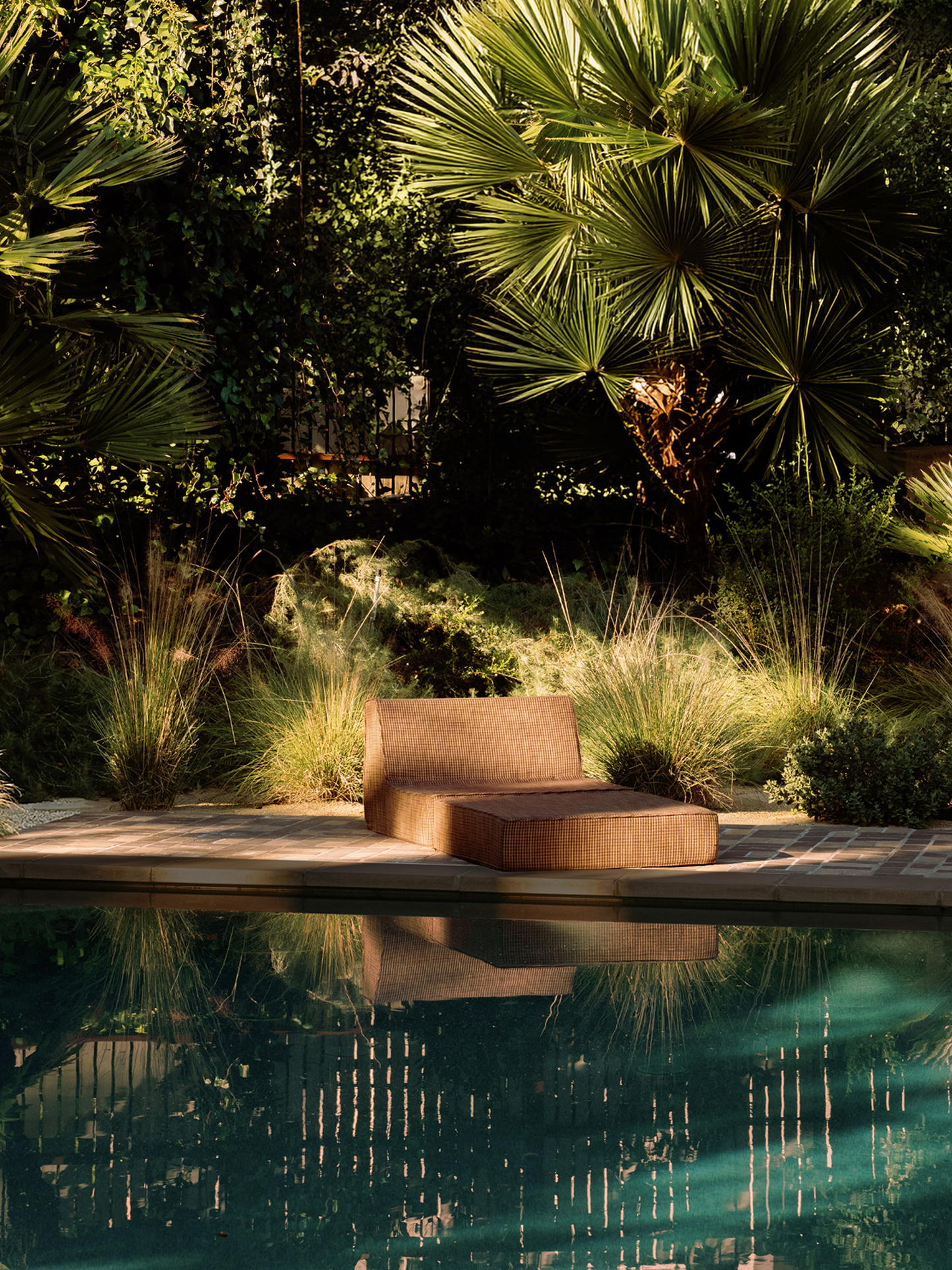 Brown folding outdoor lounge chaise by pool