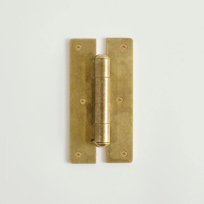 Raw brass door hinge on a light gray background