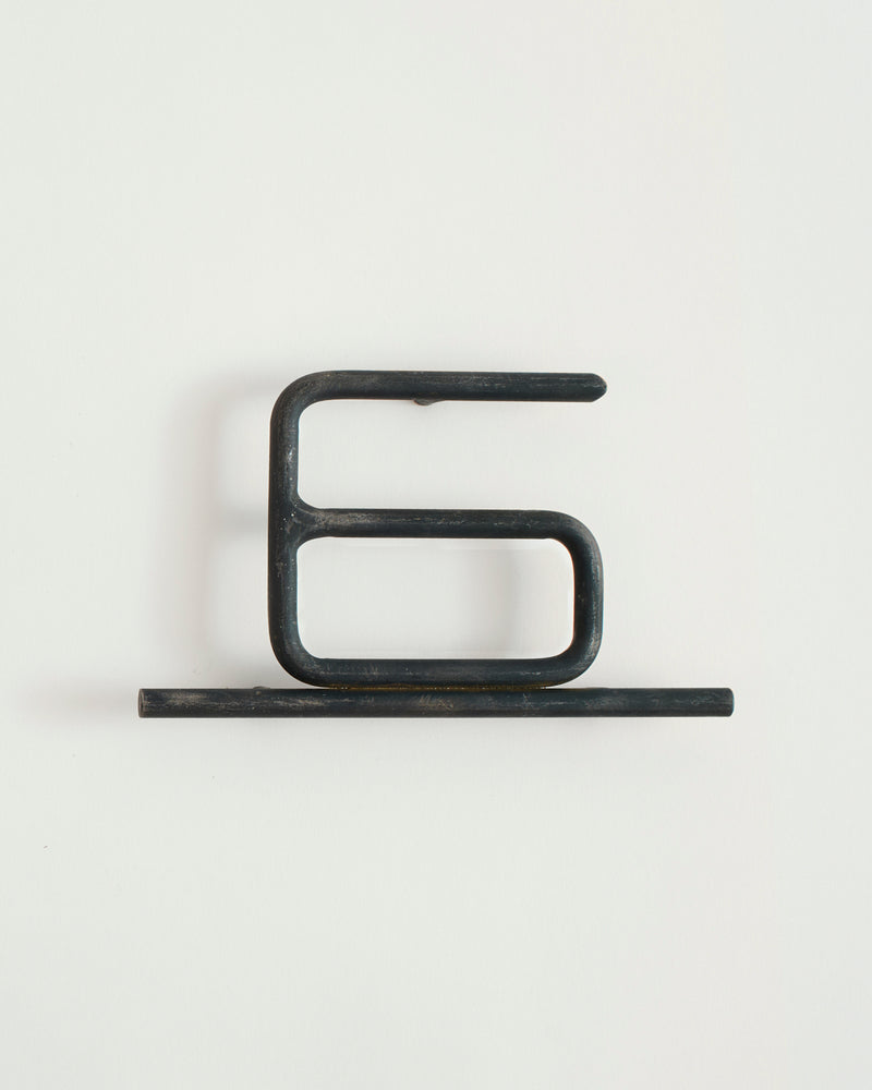 Black house number '6' on a white wall 